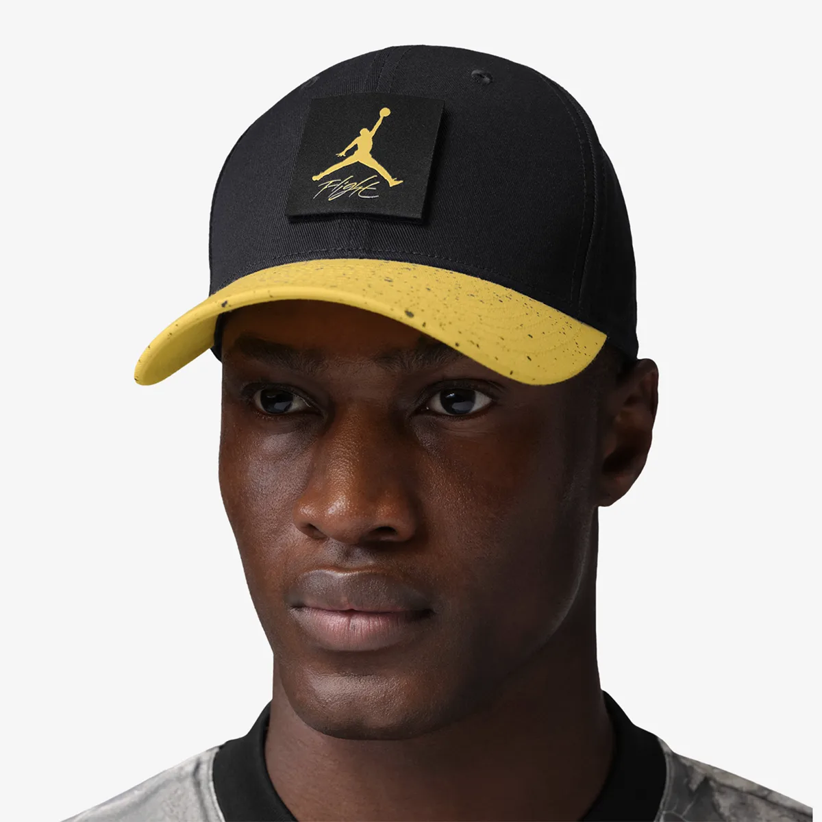 Model wearing a black Jordan Rise Tour cap with Tour Yellow speckled bill and Jumpman Flight patch.