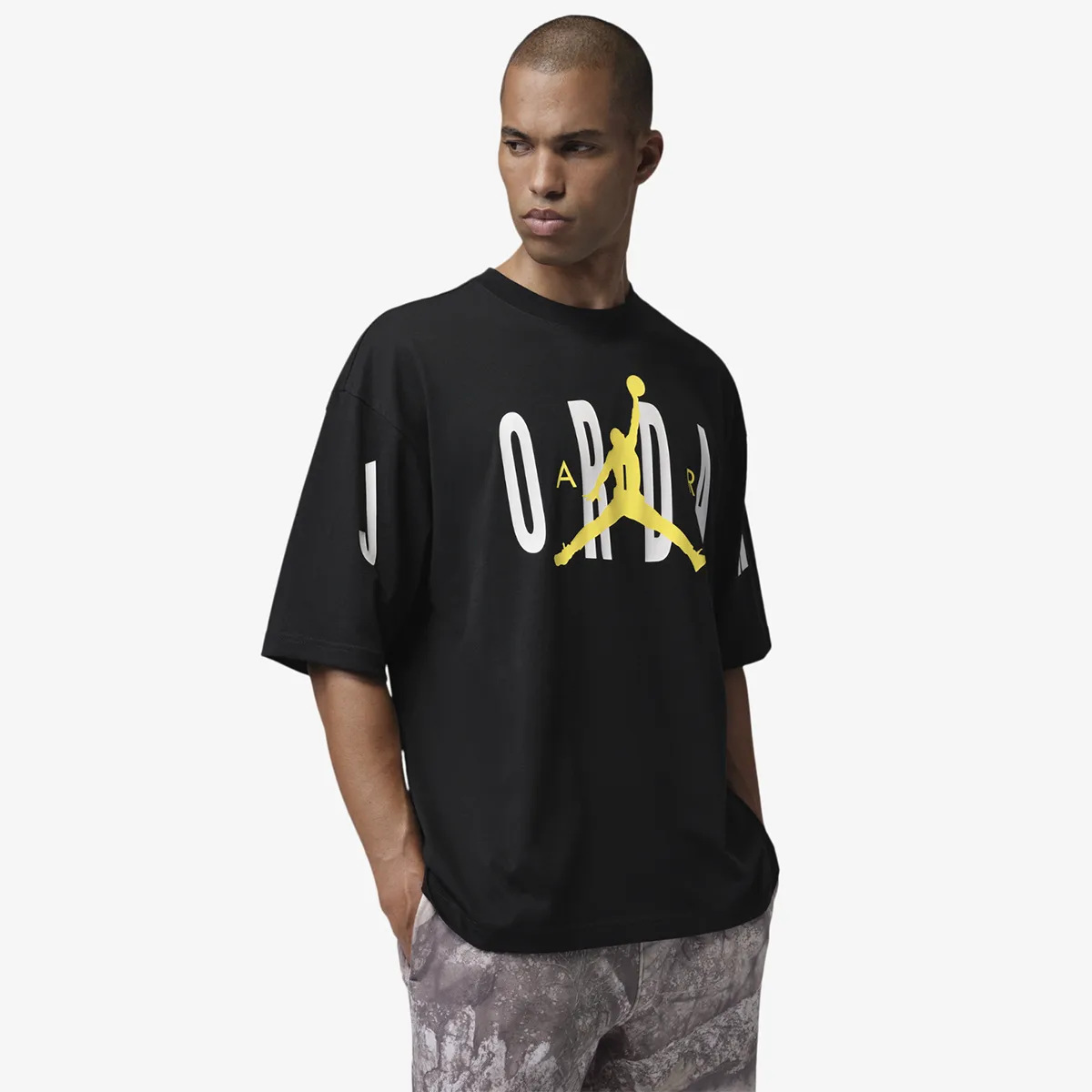 Model wearing the black Jordan Stretch Oversized T-Shirt with white Jordan lettering and a Tour Yellow Jumpman graphic.