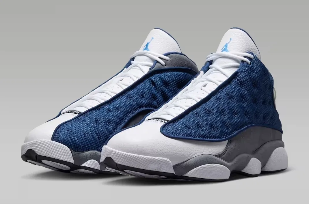 Angled view of the Air Jordan 13 "Flint" (2026) sneakers in Navy, University Blue, Flint Grey and White.