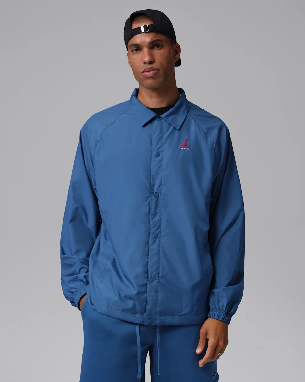 Front view of a blue Jordan Coaches Jacket paired with the Air Jordan 3 True Blue sneakers.