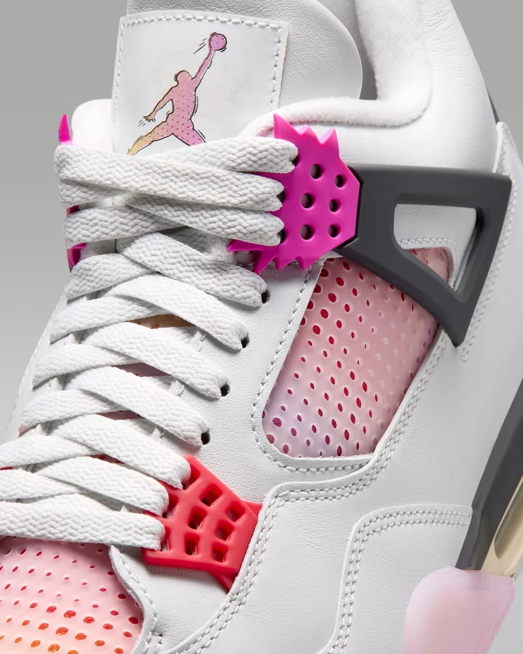 Close-up of the Air Jordan 4 Comic showing pink and red lace wings, gradient Jumpman tongue logo and comic-inspired mesh panels.