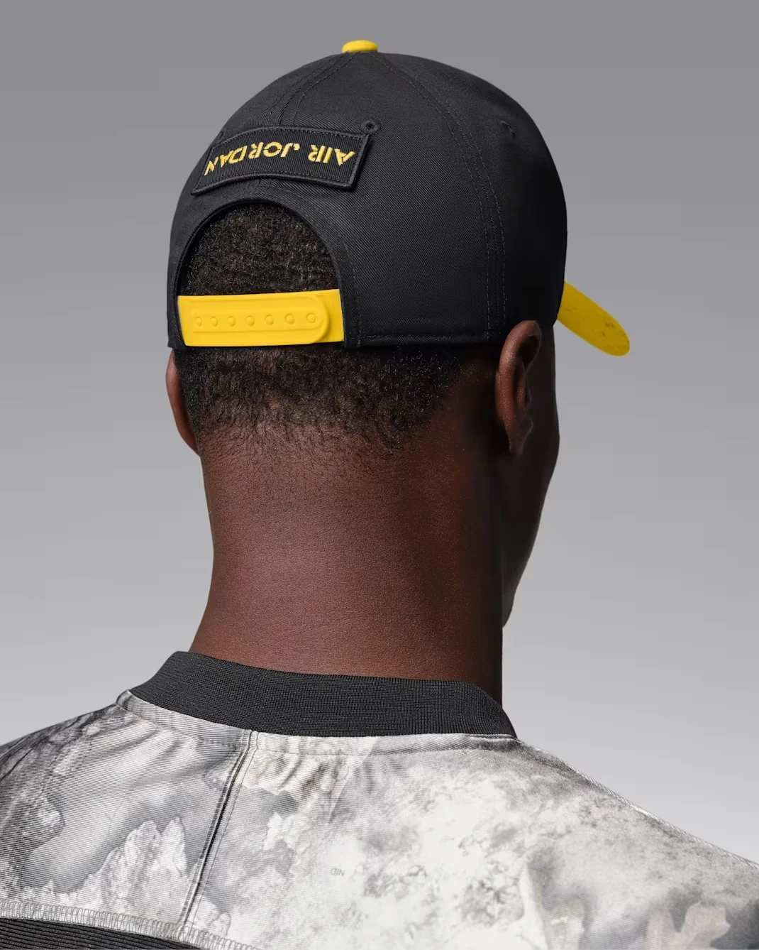 Rear view of black and Tour Yellow Jordan AJ4 Rise cap with yellow snapback closure