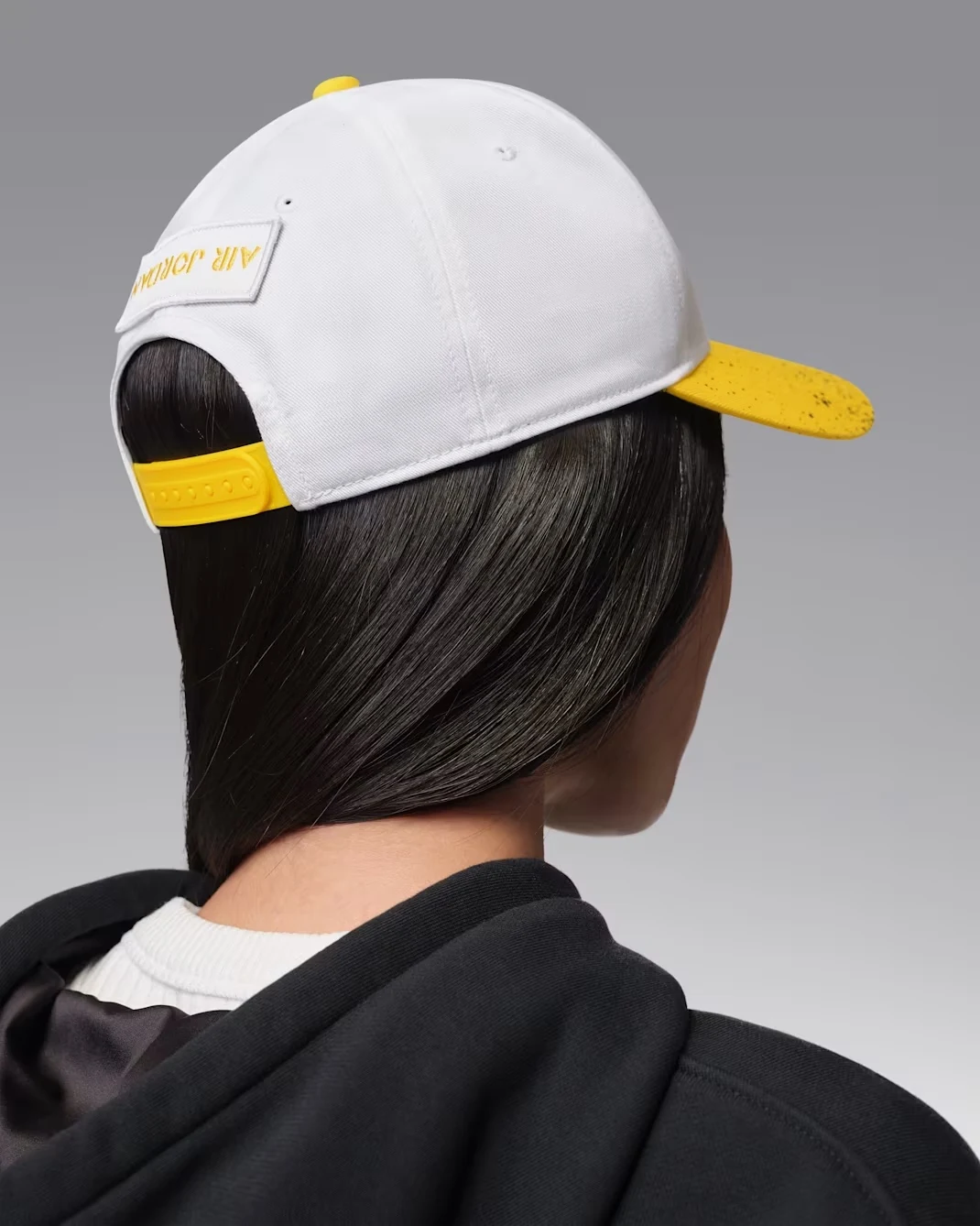 Rear view of white and Tour Yellow Jordan AJ4 Rise cap with yellow snapback closure