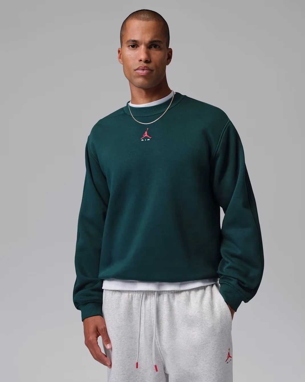 Model wearing the Jordan Brooklyn crew-neck sweatshirt in Midnight Spruce with University Red accents.