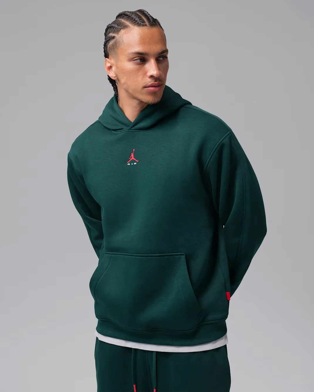 Model wearing the Jordan Brooklyn pullover hoodie in Midnight Spruce with University Red accents.