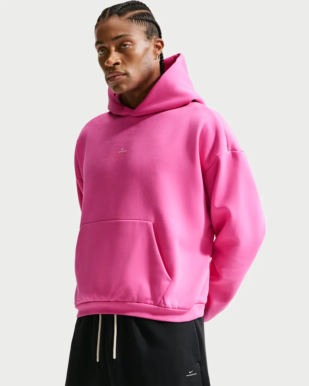 Model wearing the Nike Standard Issue Therma-FIT Brushed Basketball Pullover Hoodie in pink with black basketball pants.