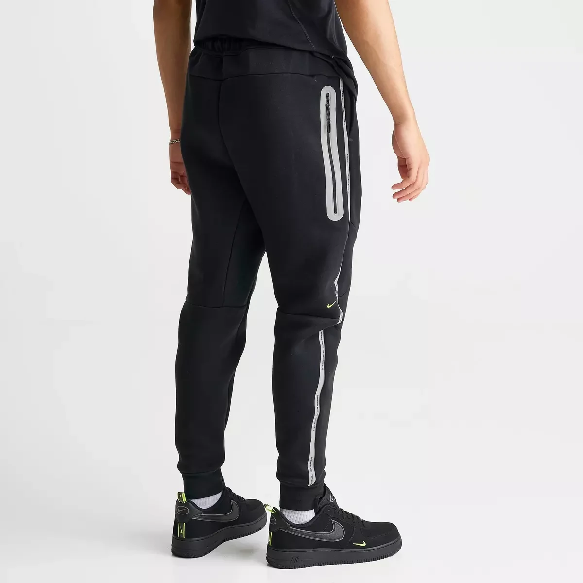 Back view of Nike Tech Fleece Reflective Jogger Pants in black with grey reflective zipper detailing and Volt accents.