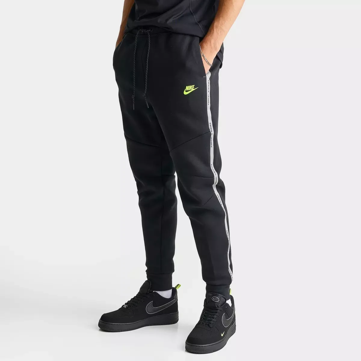 Front view of Nike Tech Fleece Reflective Jogger Pants in black with reflective grey side stripes and a Volt Nike logo.