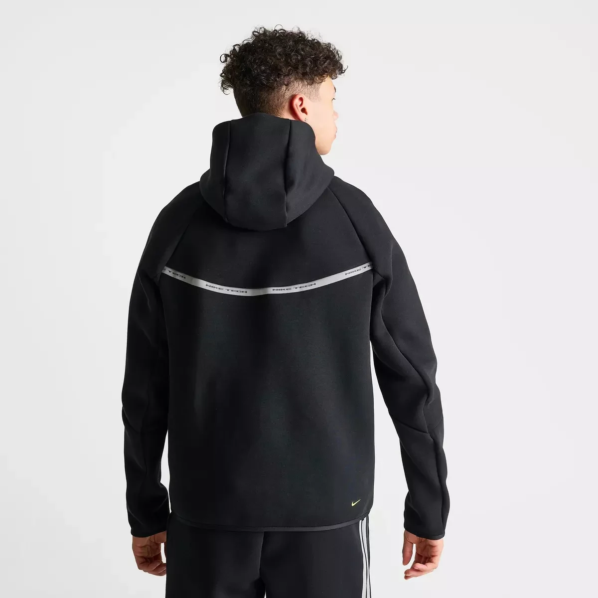 Back view of the black Nike Tech Fleece Reflective Windrunner Hoodie with a grey reflective stripe across the shoulders and Volt Nike Swoosh.