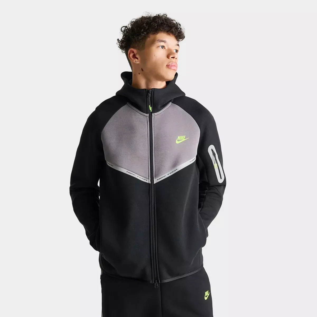 Front view of Nike Tech Fleece Reflective Windrunner Full-Zip Hoodie in black and grey with reflective detailing and Volt Nike branding.